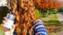 Woman with vibrant, glossy red hair holding a bottle of Save Me From Age Acceleration Tip-to-Root Hair Reboot next to her hair.